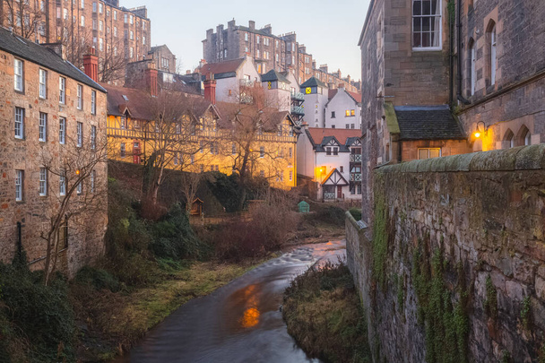 Βραδινή θέα στο νερό του Leith και τα κτίρια κατοικιών μέσω της παλιάς πόλης Dean Village στο Εδιμβούργο της Σκωτίας σε ένα σαφές απόγευμα χειμώνα. - Φωτογραφία, εικόνα