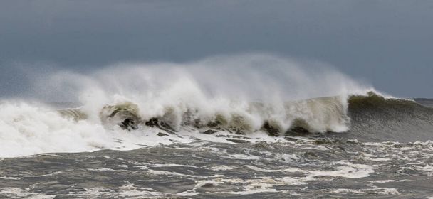 Una vista del paisaje del Océano Atlántico frente a la costa de Fire Island Nueva York con olas formadas por una tormenta tropical y vientos muy fuertes que soplan el agua hacia atrás. - Foto, Imagen