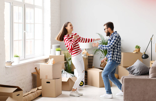 Full body side view of delighted young couple man and woman dancing and jumping happily while having fun during moving into new apartment - Fotografie, Obrázek