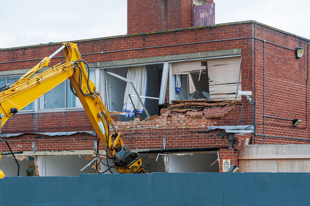 Demolition of an old building with a long reach machine hydraulic jaw. Regeneration of a space for new, modern building. - Photo, Image