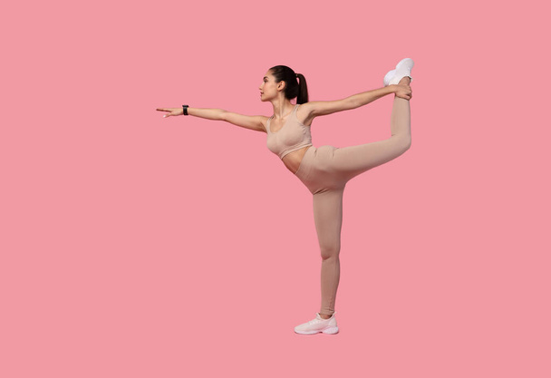 jonge vrouw doen evenwicht oefening met been verhogen - Foto, afbeelding