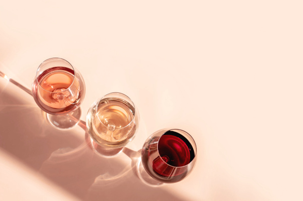 Окуляри червоного, рожевого та білого вина з ефектом сонячної тіні. Концепція дегустації вина. Плоский прошарок, вид зверху
. - Фото, зображення
