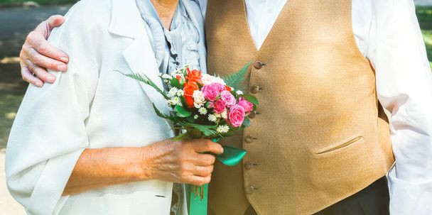 Yaşlı çift yeşil parkta yürüyor. Büyükannem ve büyükbabam altıncı evlilik yıldönümü kutlamalarında. 50 yıl birlikte yaşlıların aşk hikayesi. Büyükannem ve büyükbabam gülüyor.. - Fotoğraf, Görsel