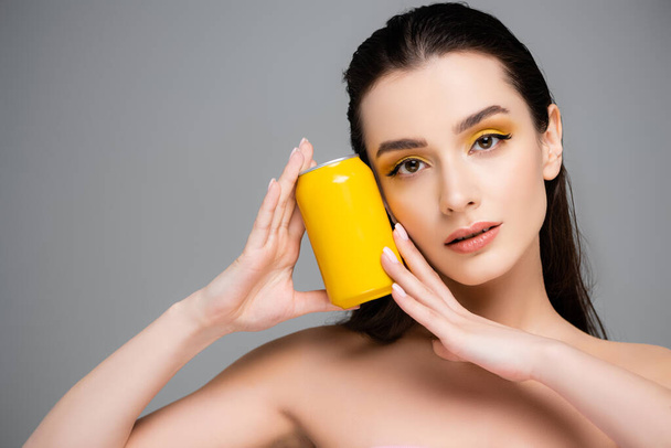brünette junge Frau mit gelber Dose mit Erfrischungsgetränk isoliert auf grau  - Foto, Bild
