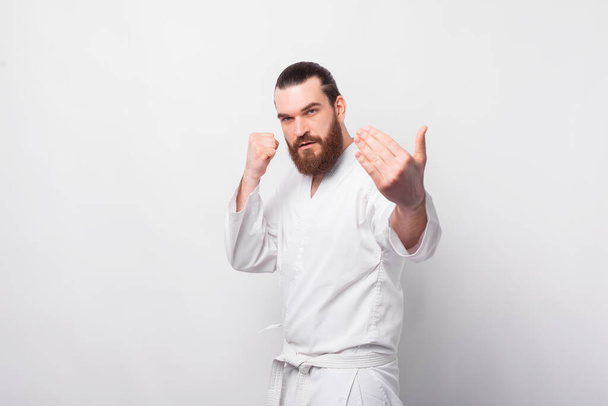 Photo of bearded man in taekwondo uniform preparing for fight, come on - Photo, Image