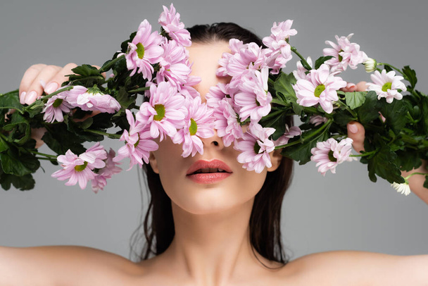young woman covering eyes with pink flowers isolated on grey - Foto, immagini