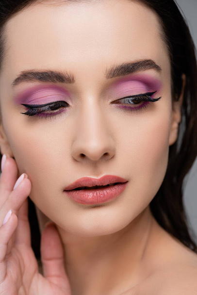 close up of brunette woman with pink eye shadows looking away isolated on grey - Fotoğraf, Görsel