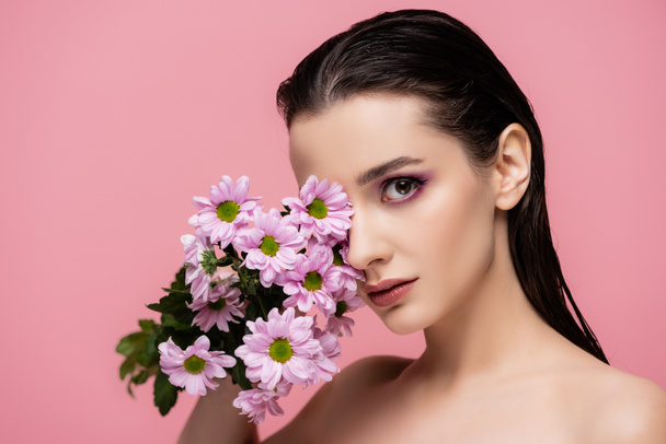 young sensual woman with bare shoulders holding flowers isolated on pink - Фото, изображение