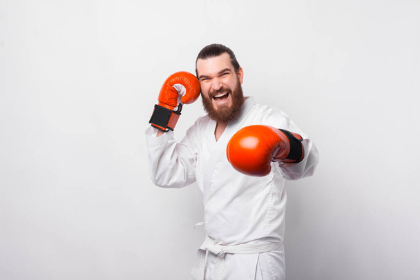 Zdjęcie uśmiechniętego mężczyzny w taekwondo jednolitego treningu na białym tle - Zdjęcie, obraz