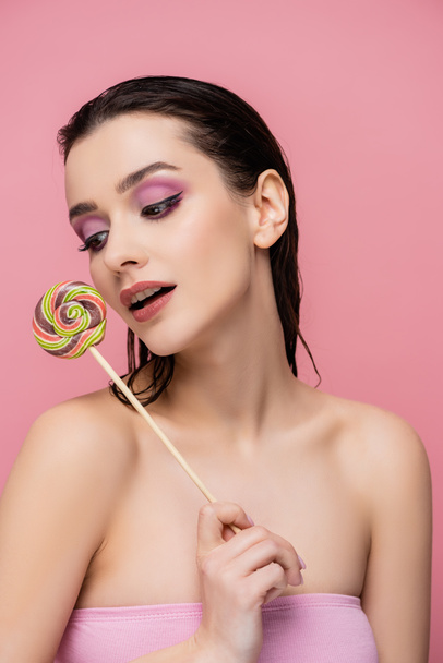 young woman with bare shoulders holding lollipop isolated on pink  - Photo, Image