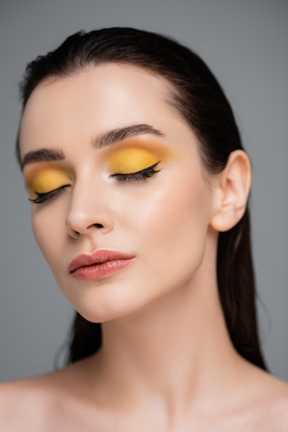 young brunette woman with yellow makeup and closed eyes isolated on grey - Fotoğraf, Görsel