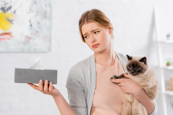 Mujer triste sosteniendo siamés gato y caja con servilleta  - Foto, Imagen
