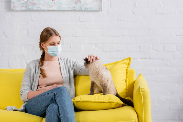 アレルギーの間に同じ猫を撫でる医療用マスクの女性  - 写真・画像