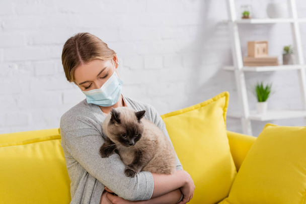 Nő -ban orvosi maszk gazdaság sziámi macska alatt allergia -ban nappali  - Fotó, kép