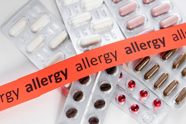 Top kilátás szalag allergia betűkkel közelében tabletták az asztalon  - Fotó, kép