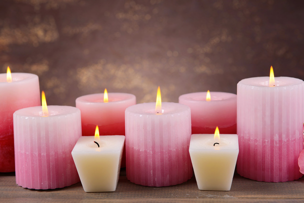 Beautiful candles on table on brown background - Фото, изображение