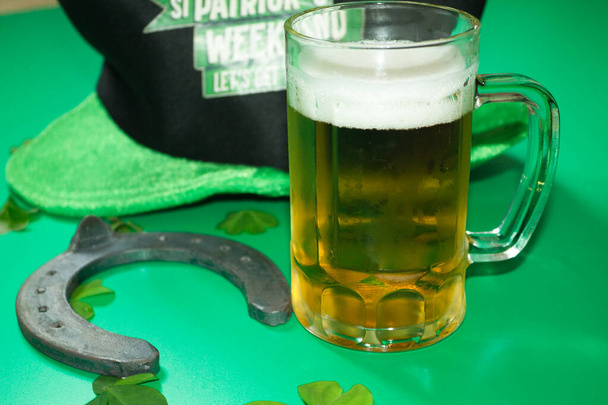 szczęśliwy podkowy i czarny i zielony kapelusz z kubek piwa na zielonym tle - Zdjęcie, obraz