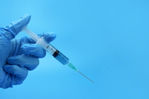 Ručně držená injekční stříkačka s lékem na modrém podkladu - Fotografie, Obrázek