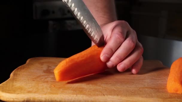 trancher les carottes. homme coupe des carottes sur une planche à découper. Cuisiner à la maison. - Séquence, vidéo