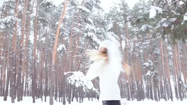 Menina sorridente bonita na floresta de inverno. Posando em uma camisola branca, chapéu e luvas - Filmagem, Vídeo