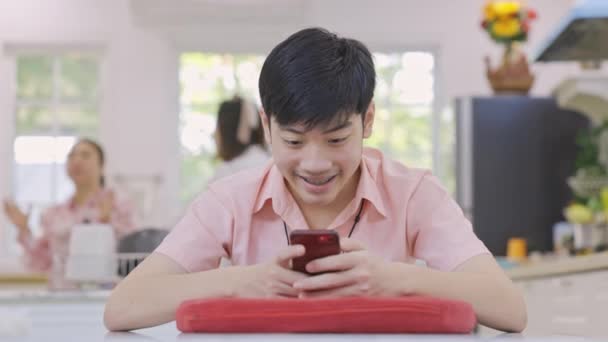Aziatisch middelbare school jongen speelt online spel op zijn mobiele telefoon thuis. - Video