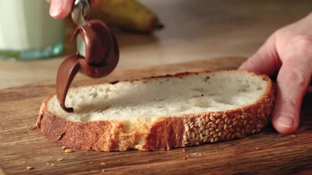 Frauenhände tragen Schokonusscreme auf eine Scheibe frisch gebackenes Brot aus nächster Nähe auf. Hausmannskost-Frühstück - Filmmaterial, Video