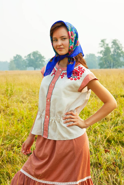 girl in traditional clothes and kerchief on meadow - Photo, Image