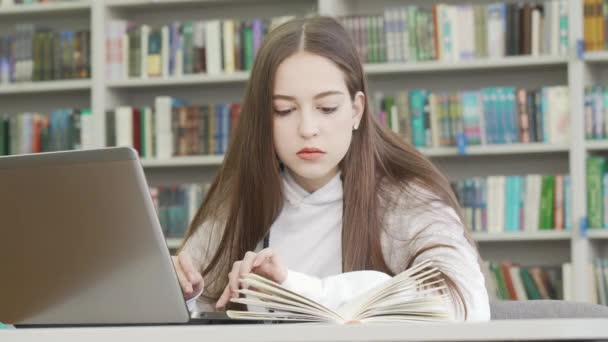 Teini-ikäinen tyttö käyttää tietokonetta kirjastossa - Materiaali, video