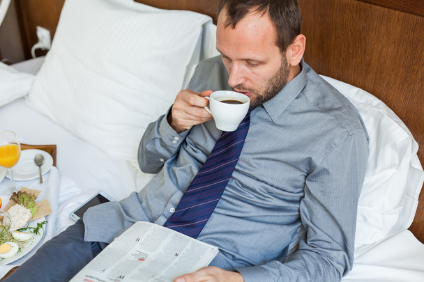 Businessman drinking coffee and reading newspaper - Fotografie, Obrázek