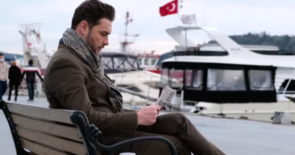  businessman reading newspaper while sitting on bench, reads world news.Bebek - Кадры, видео