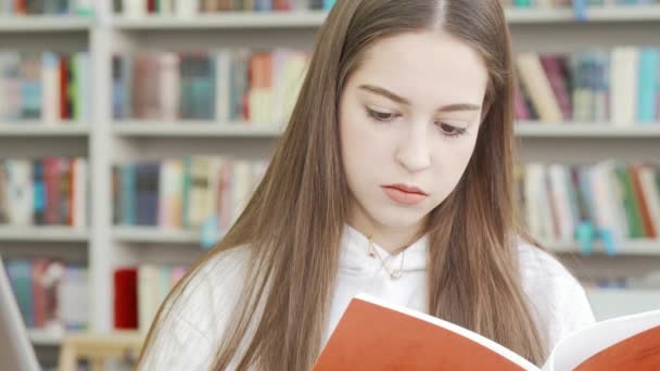 Μια έφηβη διαβάζει ένα βιβλίο στη βιβλιοθήκη. - Πλάνα, βίντεο