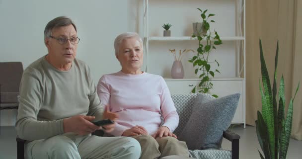 Běloši starší pár důchodců tráví víkend doma sledování hry v televizi povzbuzování jejich oblíbeného týmu budování ztratit špatné skóre naštvaný starý muž hází dálkové ovládání z nespokojenosti - Záběry, video