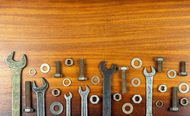 Nolling style photo - Different wrenches, bolts, nuts and washers on brown wood texture background - Photo, Image
