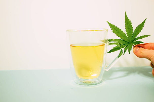 Cannabis thee in een doorzichtig kopje. Medische marihuana blad. Homeopathisch kruid. Stressverlichting therapie. Kopieerruimte - Foto, afbeelding