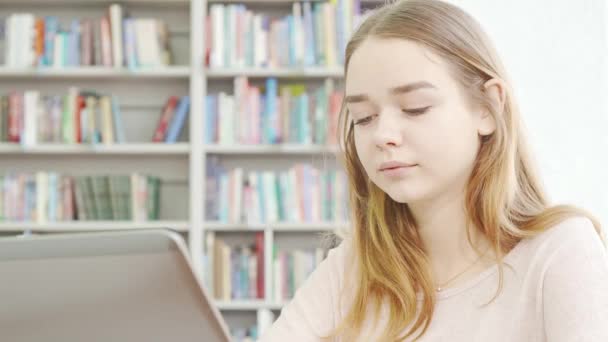 Linda menina adolescente usando laptop na biblioteca - Filmagem, Vídeo