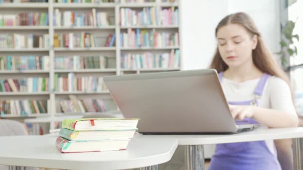 Selektiivinen keskittyä kirjoihin teini tyttö käyttäen kannettavaa taustalla - Materiaali, video
