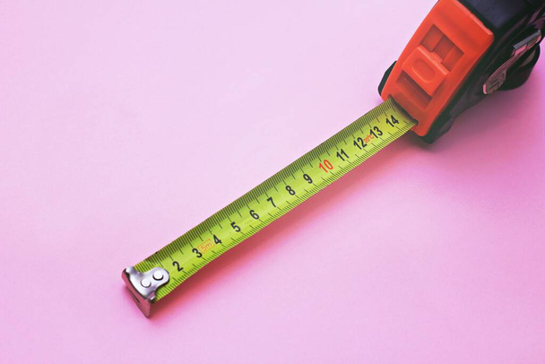 An old metal measuring tape on pink background. Copy space, selective focus. - Photo, Image