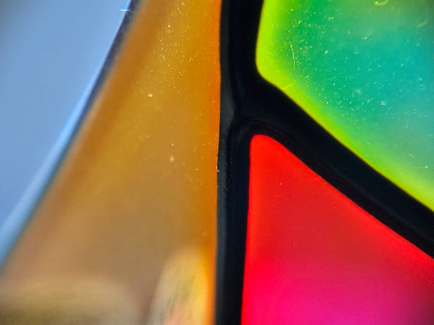 Green, blue, golden and red segments of a glass candle stand seen very close - Photo, Image