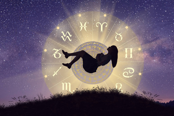 Astrologische Tierkreiszeichen innerhalb des Horoskopkreises. Frau, die über dem Tierkreisrad mit Mandala und Milchstraßenhintergrund laviert. Die Macht des Universums-Konzepts. - Foto, Bild