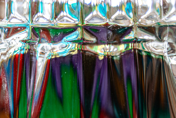 Um copo de uísque invertido com um suporte de vela cria padrões muito impressionantes de cor - Foto, Imagem