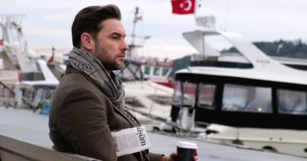 Feliz hombre de negocios leyendo el periódico mientras está sentado en el banco, lee noticias turcas - Metraje, vídeo