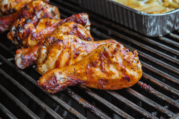 Grilled chicken on barbeque grill macro, delicious meat cooked on wooden charcoals with smoke - Photo, Image