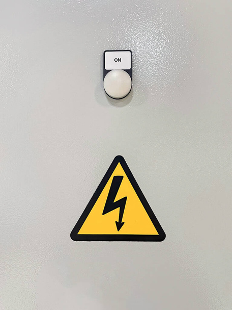 detail van een machine met een licht met het bericht "aan" en een waarschuwingssymbool voor hoogspanning, verticaal - Foto, afbeelding