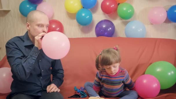Papa und Tochter blasen rosa Luftballon auf und spielen damit - Filmmaterial, Video