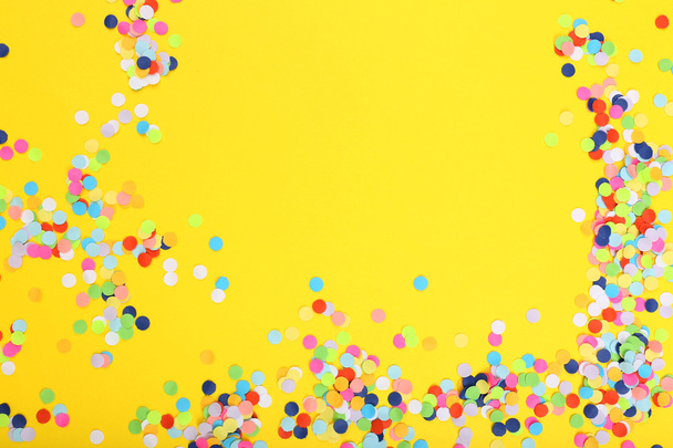 Confetti on yellow background - Foto, afbeelding