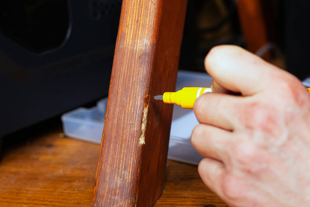 restaurování a oprava dřevěného nábytku mistrovská ruka uzavře škrábanec speciálním značkovačem - Fotografie, Obrázek