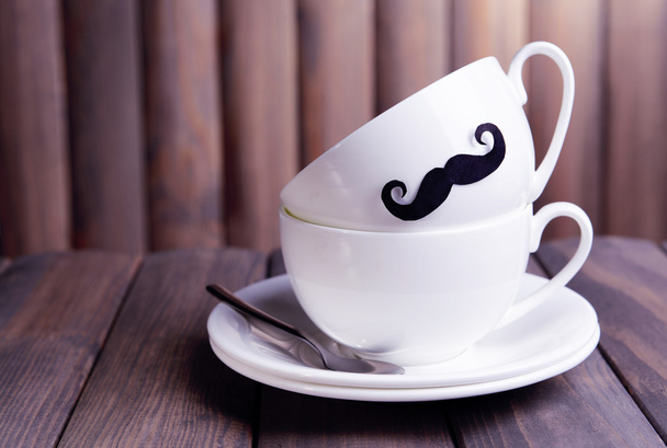Cup with mustache on table on wooden background - Fotoğraf, Görsel