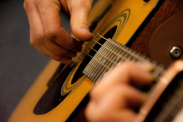 Гітарна палуба та гітарні руки крупним планом. Капо на дошці гітари. Розмитий гітарний фон
 - Фото, зображення