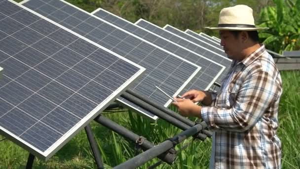 Los agricultores asiáticos utilizan tabletas para ajustar el grado de las células solares y comprobar el rendimiento de las células solares después de la lluvia y manchas de polvo y suciedad en la célula solar. Concepto de tecnología agrícola. - Metraje, vídeo
