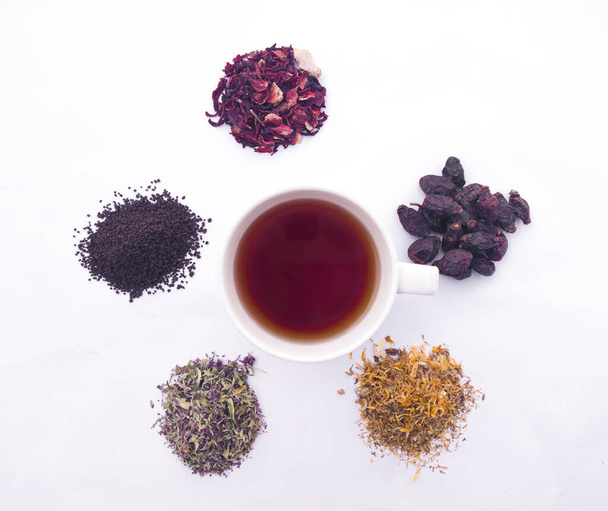 Una taza de té y una variedad de hierbas y bayas secas - Foto, Imagen